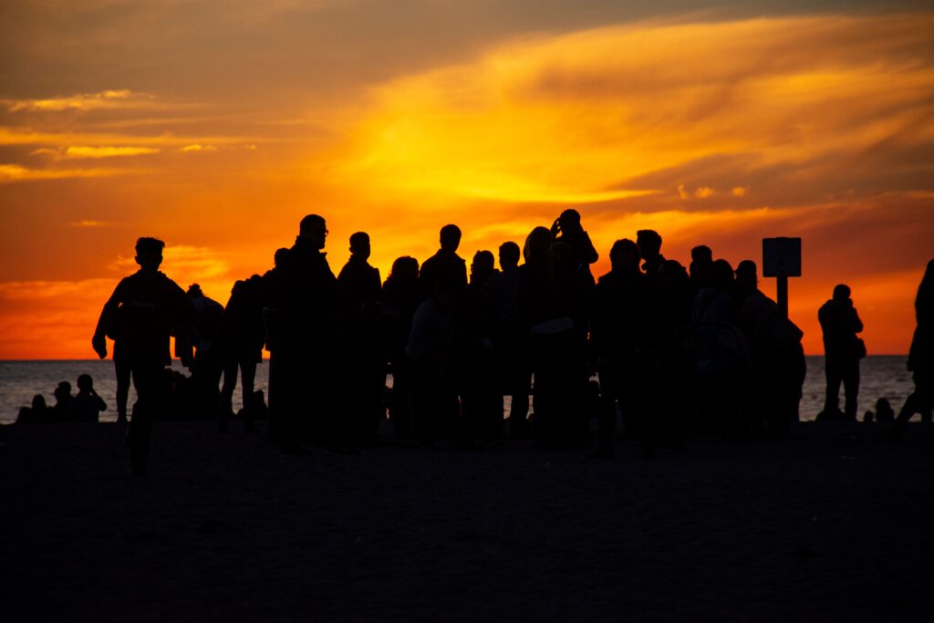 pexels-photo-2935914-2935914 Silhouettes of a group gathered on Santa Monica beach with a striking orange sunset.